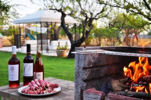twee flessen wijn en een bord vlees naast een vuur bij PalmaFlora villa con trulli in Impalata