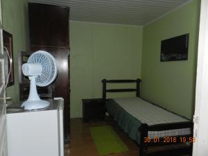 a small bedroom with a bed and a fan at Morada do Estudante in Pelotas