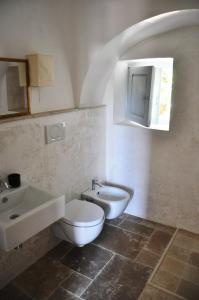 a bathroom with a white toilet and a sink at PalmaFlora villa con trulli in Impalata