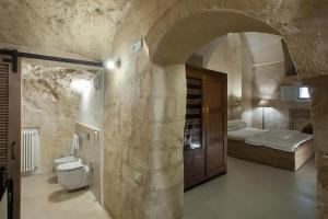 una camera da letto con letto e servizi igienici in un muro di pietra di L'Hotel In Pietra a Matera