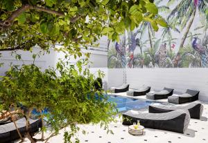 a courtyard with a pool with chairs and trees at Vasia Boulevard Hotel (Adults Only) in Hersonissos