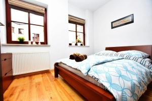 a bedroom with a bed and two windows at City Central Apartments Wrocław in Wrocław