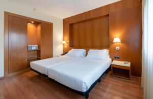 托爾托薩的住宿－貝倫格爾四世酒店，卧室设有白色大床和木墙