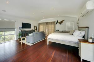 a bedroom with a bed and a couch and a television at Coastal Hideaway in South West Rocks