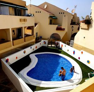 una piscina en el medio de un edificio con dos personas en él en Mareverde, Costa Adeje, pool view terrace en Adeje