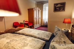 a hotel room with two beds and red chairs at Hotel und Restaurant Golden Village in Riesa