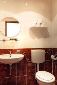 a bathroom with a toilet and a sink and a mirror at Hotel und Restaurant Peking in Riesa