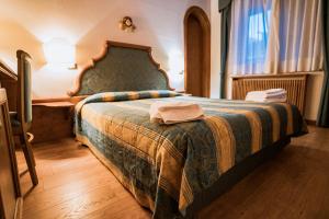 een slaapkamer met een bed met een deken erop bij Hotel Sporting in Val di Zoldo