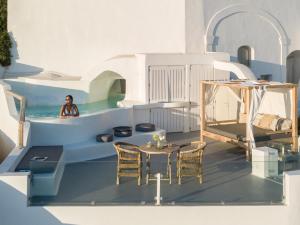 a woman in a pool with a table and chairs at Cocoon Suites in Imerovigli