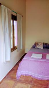 1 dormitorio con cama morada y ventana en apartamento VINTAGE LU en Merlo