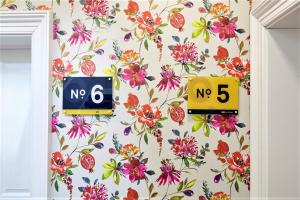 a room with a floral wallpaper with no and two clocks at Rowan Tree - Your Apartment in Bristol