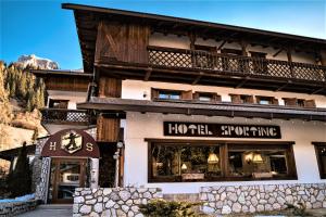 ヴァル・ディ・ゾルドにあるHotel Sportingのホテルの雪スキーを読む看板のある建物の正面