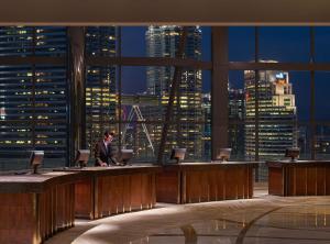 a man sitting at a desk in a large room with a city skyline at Grand Hyatt Kuala Lumpur in Kuala Lumpur