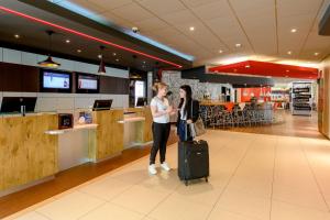 two women standing with their luggage in a restaurant at ibis Zürich City West in Zürich