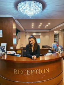 a woman sitting at a reception desk in an office at Hotel Vlaho in Skopje