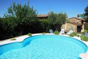 una piscina in un cortile con sedie e una casa di Tuscan Charme of Cottage Roccaio Countryside Cortona a Castiglion Fiorentino