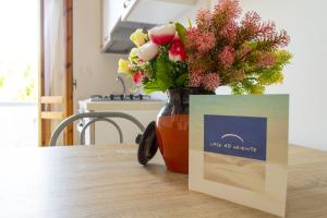 a vase of flowers sitting on a table with a card at Residence Borgo Latino- Localo in Torre dell'Orso
