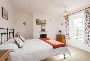 a white bedroom with a bed and a window at Jurassic Cottage in Portesham