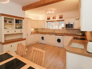 a kitchen with white cabinets and a table with chairs at Levenbeck Cottage in Whitby