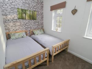 two twin beds in a room with a brick wall at Levenbeck Cottage in Whitby