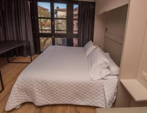 a bedroom with a white bed and a window at Apartamentos Puerta de Llanes in Llanes