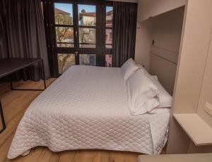 1 dormitorio con cama blanca y ventana en Apartamentos Puerta de Llanes, en Llanes