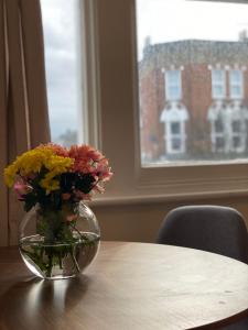 un jarrón de flores sentado en una mesa en apartment Lavender Hill, en Londres