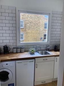 uma cozinha com um lavatório e uma janela em apartment Lavender Hill em Londres
