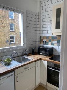 cocina con fregadero y microondas en apartment Lavender Hill, en Londres
