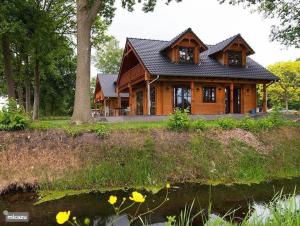 a wooden house with a pond in front of it at Houten Villa Dirk in Den Ham