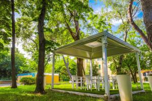 un kiosque avec des tables et des chaises blanches dans un parc dans l'établissement Villa Bellini, à Porto Garibaldi