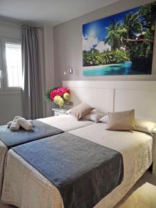 two beds in a bedroom with a painting on the wall at Hostal Bodega in Conil de la Frontera
