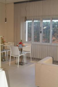 comedor con sillas blancas, mesa y ventanas en B&Beach Cagliari guest house, en Cagliari