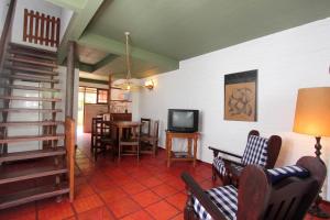 ein Wohnzimmer mit Fernseher und Tisch und Stühlen in der Unterkunft Ron Apartamentos Duplex in La Paloma