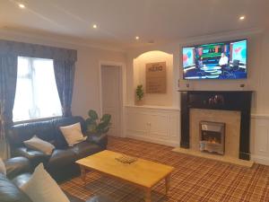 a living room with a couch and a tv at Valley Grove Bungalows in Saundersfoot