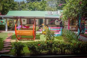Hotel Marielos في تاماريندو: حديقة بها مرجيحة و منزل به زهور