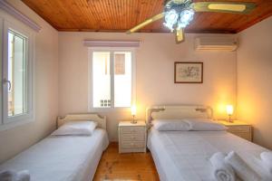 two beds in a room with two windows at Traditional Village House in Méson Yerakaríon