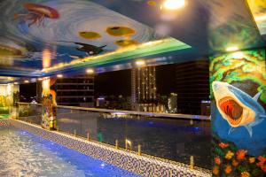 a large swimming pool in a building with a painting of a fish at Money Fine Quy Nhơn - Khách sạn dát vàng in Quy Nhon
