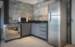 a kitchen with a stainless steel refrigerator and a microwave at Innbox - Canasvieiras 2 in Florianópolis
