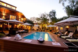 una piscina en un hotel con mesas y sombrillas en Roof of Africa Hotel en Windhoek