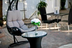 una silla y una mesa con un jarrón de flores. en Roof of Africa Hotel en Windhoek