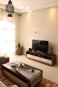 sala de estar con TV de pantalla plana y sofá en Hara Appart Luxe famille uniquement en Saidia 