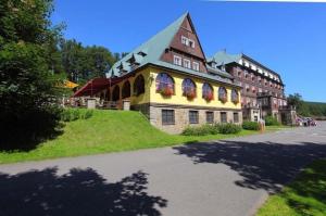 un grand bâtiment avec des fleurs à l'avant dans l'établissement Hotel Tanecnica, à Pustevny