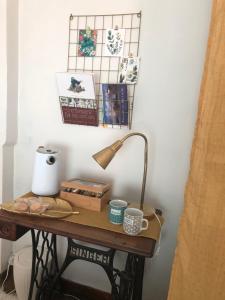 a table with a lamp and pictures on a wall at ardoises et agapanthes in Pleslin-Trigavou