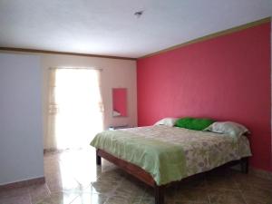 ein Schlafzimmer mit einem Bett mit einer rosa Wand in der Unterkunft Casa GoEs in Comitán de Domínguez
