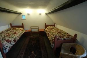 a small room with two beds and a chair at Chestnut Cottage in Eardisley