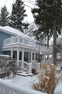 une maison blanche avec une terrasse couverte dans la neige dans l'établissement The Inn at Union Pier, à Union Pier