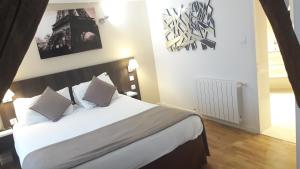 sypialnia z dużym łóżkiem z białą pościelą i poduszkami w obiekcie Hôtel Mazagran w Paryżu