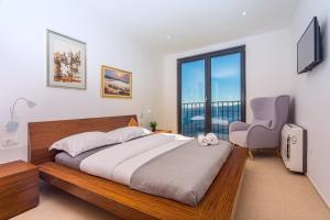 a bedroom with a large bed and a chair at Villa Mia with private pool, Whirlpool, gym, sauna, seaviews in Lokva Rogoznica +42 photos