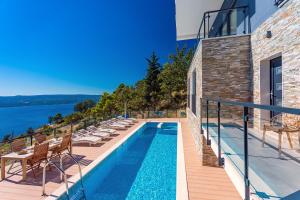 een zwembad aan de zijkant van een gebouw met stoelen eromheen bij Villa Mia with private pool, Whirlpool, gym, sauna, seaviews in Lokva Rogoznica